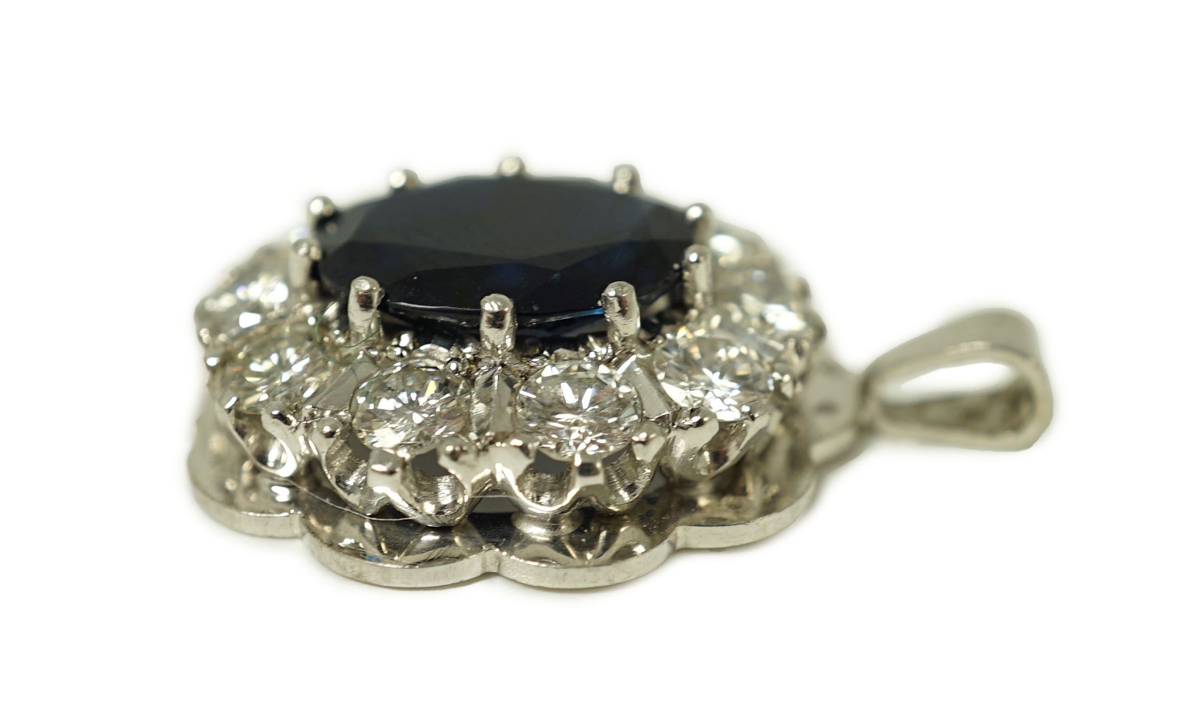 A modern 18ct white gold, sapphire and diamond set oval cluster pendant